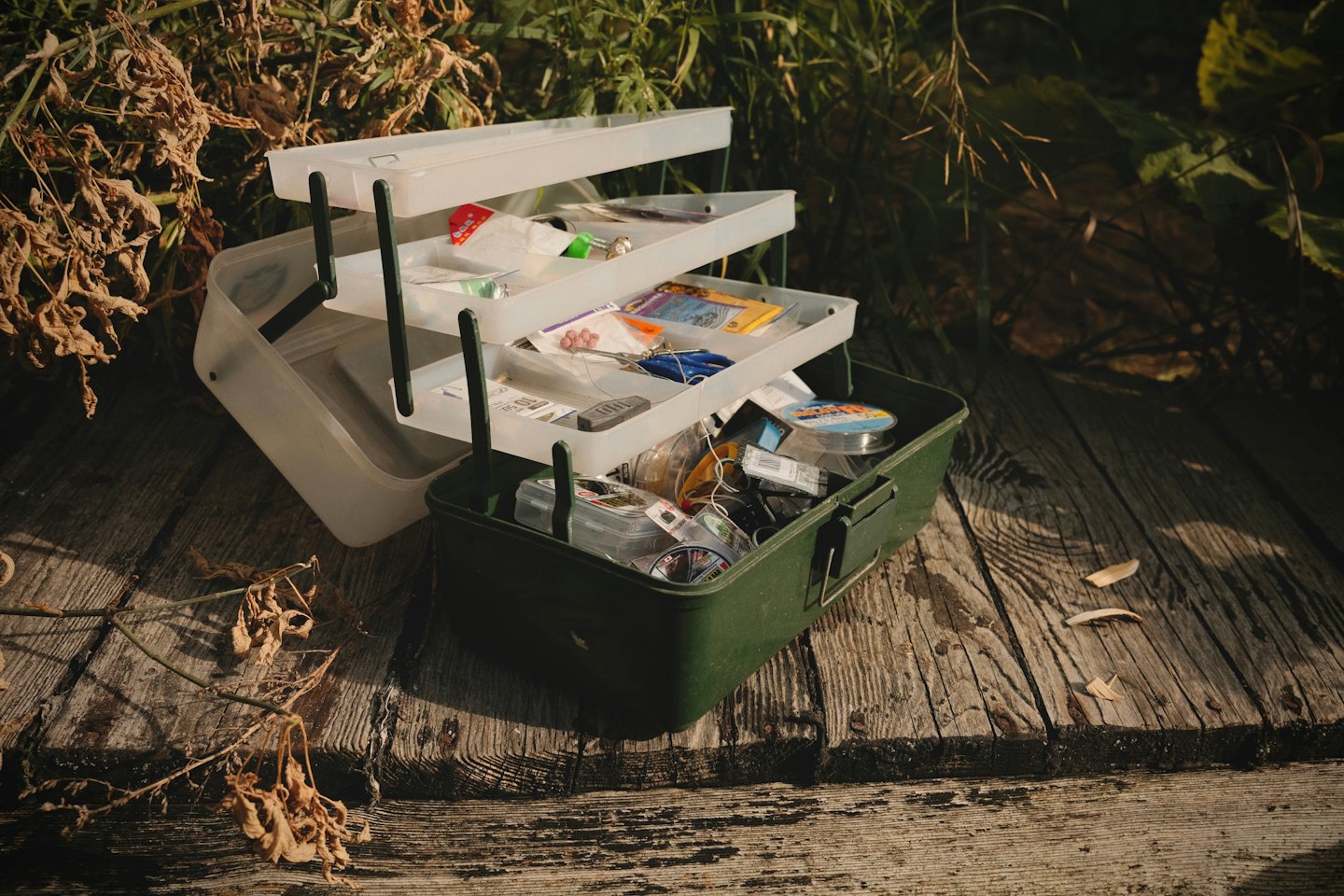 Services An open green tackle box sits filled with fishing gear on a wooden dock.