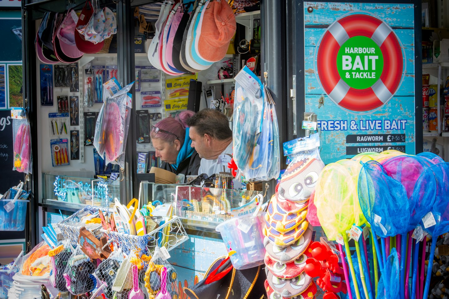 Two customers browsing fishing gear at an outdoor tackle shop.
